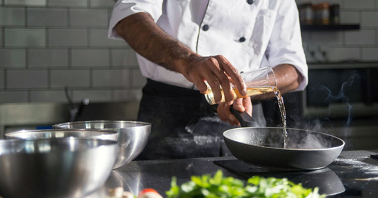 Chef pouring oil into a pan